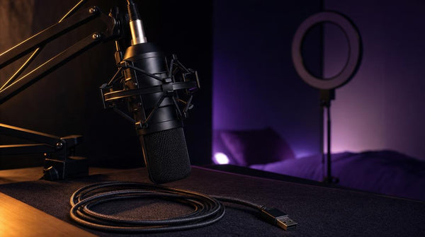 Boom-arm microphone and coiled cable on a dark desk mat, representing a small streamer's kick stream overlay setup.